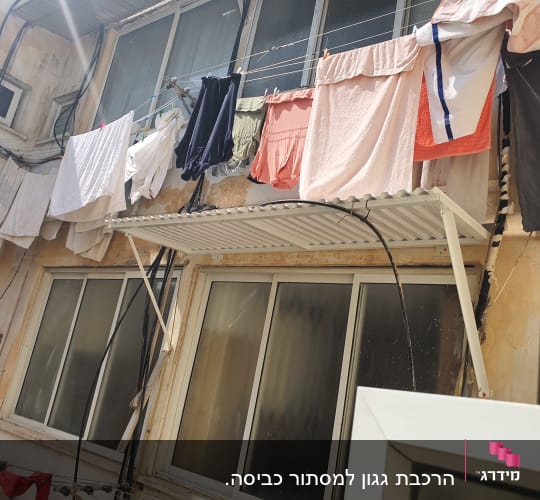 גגון אלומיניום מעל חלון עם כביסה תלויה